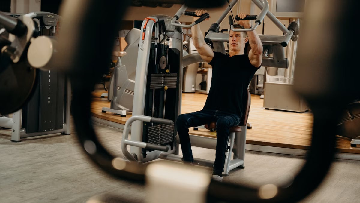 A man working out on a gym machine, focusing on upper body strength training.