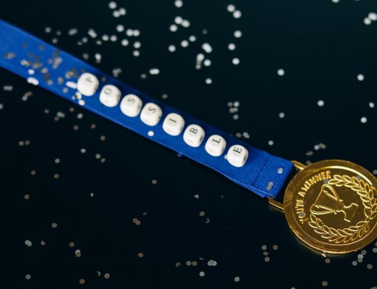 Close-up of a gold medal on a blue ribbon with 'possible' beading, symbolizing achievement.